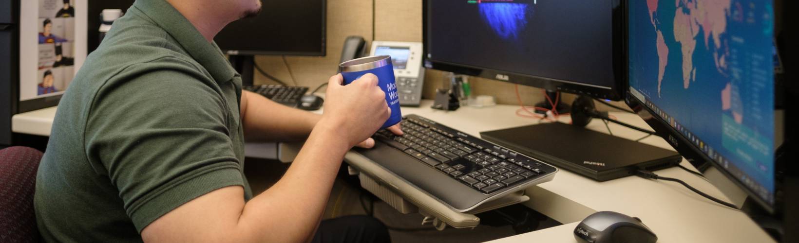 A man drinking coffee while working on his computer